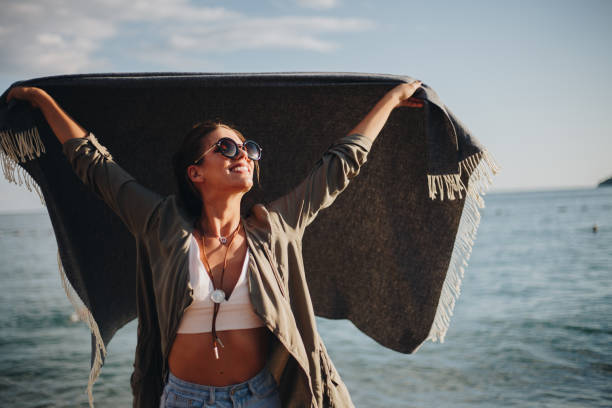 istock Millennial girl with blanket  by the beach 940693450