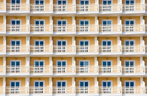 Yellow hotel exterior with small balconies and windows tourism background, Spain.