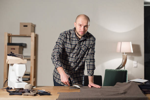 istock Cutting wool fabric. the line pattern. Bow ties of woolen fabric. Young man working as a tailor and using a sewing machine in a textile studio. 940700236