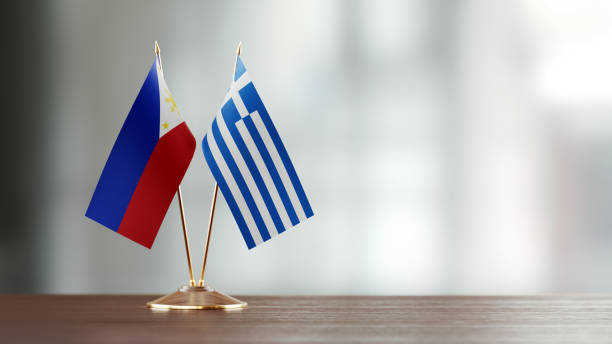istock Philippines And Greek Flag Pair On A Desk Over Defocused Background 940705792