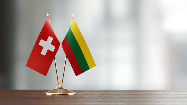 istock Swiss And Lithuanian Flag Pair On A Desk Over Defocused Background 940712578