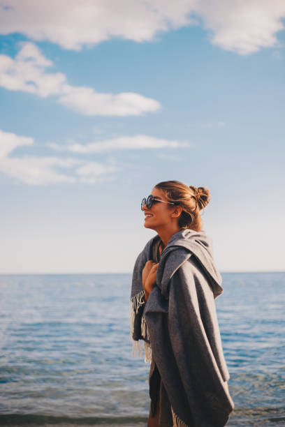 istock Millennial girl with blanket  by the beach 940713626
