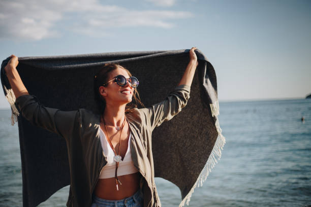 istock Millennial girl with blanket  by the beach 940719544