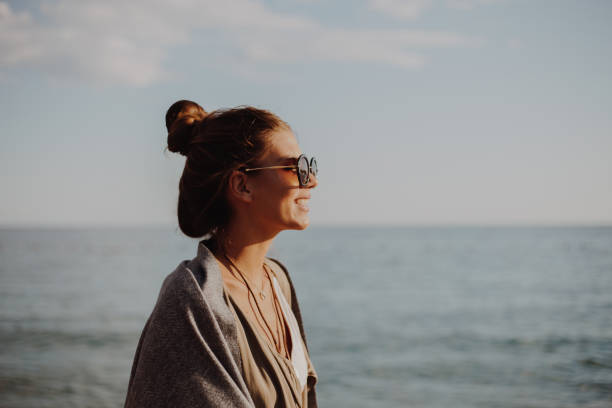 istock Millennial girl with blanket  by the beach 940723014