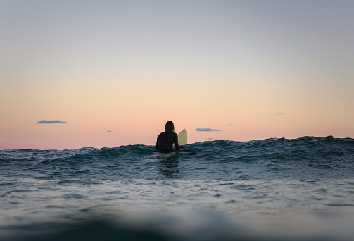 Surfer floating on the surface of the water at sunset, Bondi Beach Australia