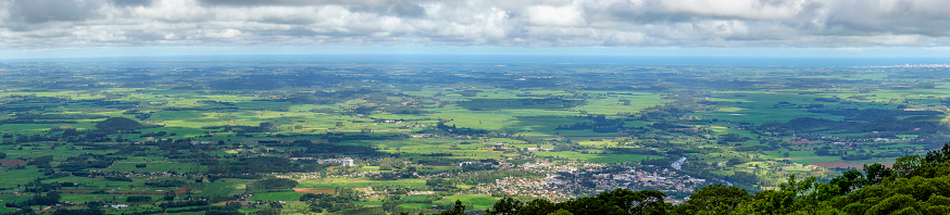 High angle view of the coastal plains of Rio Grande do Sul State, Brazil. Overcast sky and a lush forest are natural borders. The sea can be seen in the background.