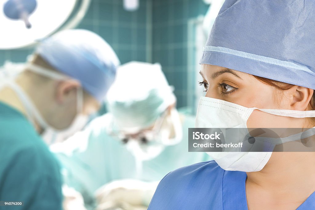 Femmina chirurgo con team chirurgico - Foto stock royalty-free di Blu