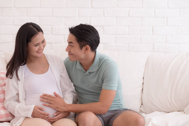 pregnant woman and her husband Pregnant women with her husband feeling happy, father is  touching to the baby in mothers womb. asian men pregnancy stock pictures, royalty-free photos & images