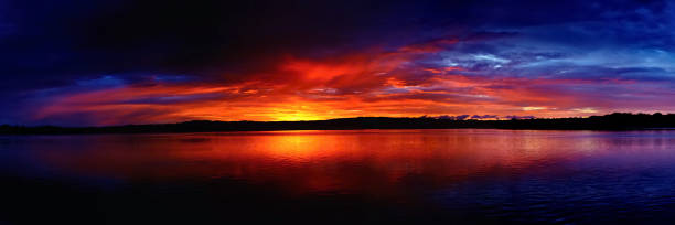 Dramatic Gold & Blue cloudy sunrise over ocean water.