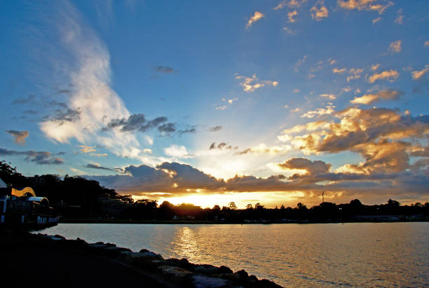 A spectacular inspirational brightly coloured cloudy sea water tropical panoramic sunrise seascape featuring silhouettes with ocean water reflections. Gosford, New South Wales, Australia.
