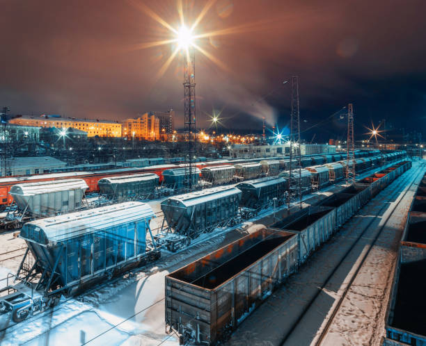 Freight railroad cars stand in parallel in winter and at night under the light of the fagots