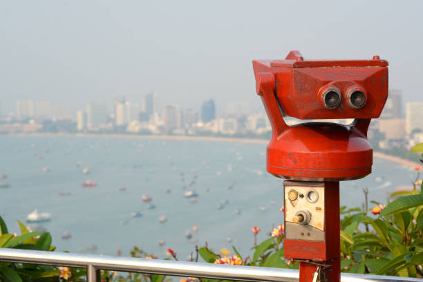 istock Binoculars red work if pick the coin inside see the seascape town and building 940791598