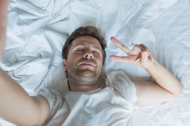 istock handsome man in white shirt taking a selfie in bed 940827110