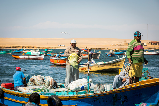Paracas, Peru - November 23, 2016: Colourful fishing boats anchored in Paracas Bay, Peru. Paracas is a small port town catering to tourists visiting Paracas Reserve and Ballestas islands.