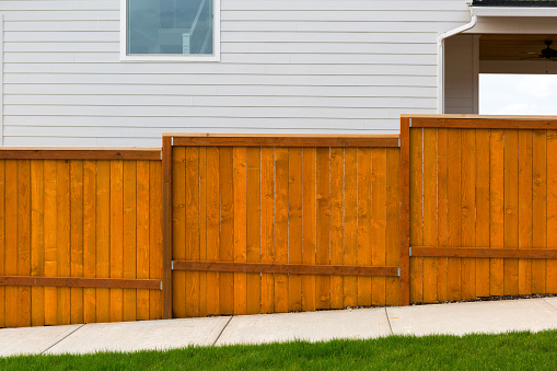 New home backyard red stained cedar wood fence construction in subdivision residential home