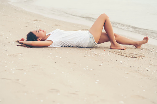 Asian young girl lying down on the beach alone