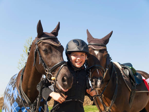 smilling giovane ragazza felice dopo aver vinto la competizione showjumping con i suoi due cavalli - horse child pony little girls foto e immagini stock