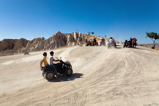 Cappadocia, Turkey, September 3, 2017: A group of tourists on quad bikes in the background of a mountain.