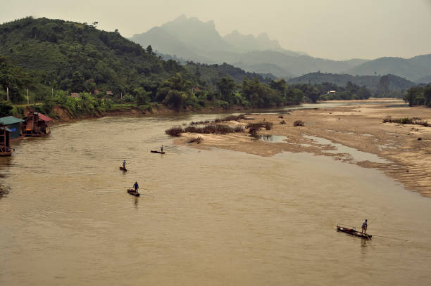 Fishermen riding motorized rafts with a v-shaped net attached to the prow of their boat, zjg jag across the Lo river, in an attempt to snare bream and other freshwater fish species into their nets.
