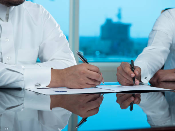 Two Saudi Businessmen Hands Signing a document, contract or making a deal stock photo