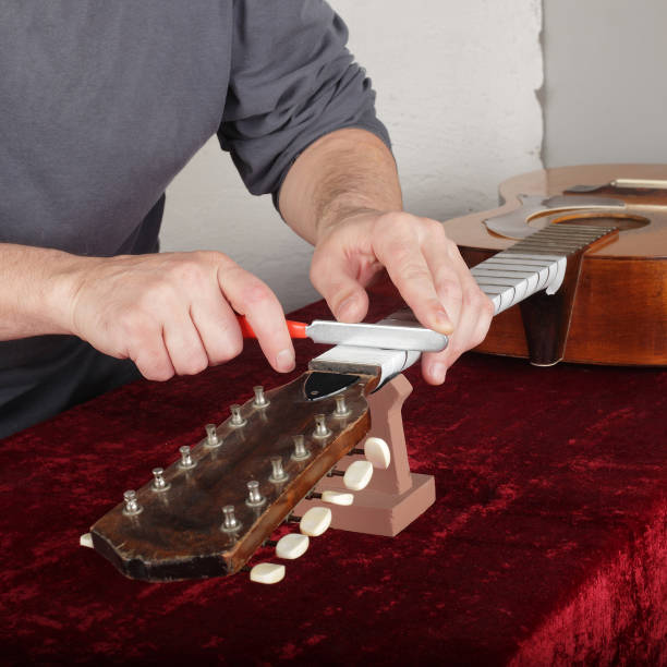 istock Guitar repair and service - Worker sharpen special tool bridge servo nut 940875534