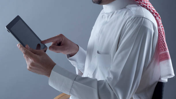 Saudi Arabian Man Holding and Using Tablet stock photo