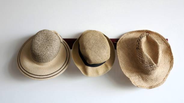 istock Three cool straw hats are hanging on a white wall 940880040