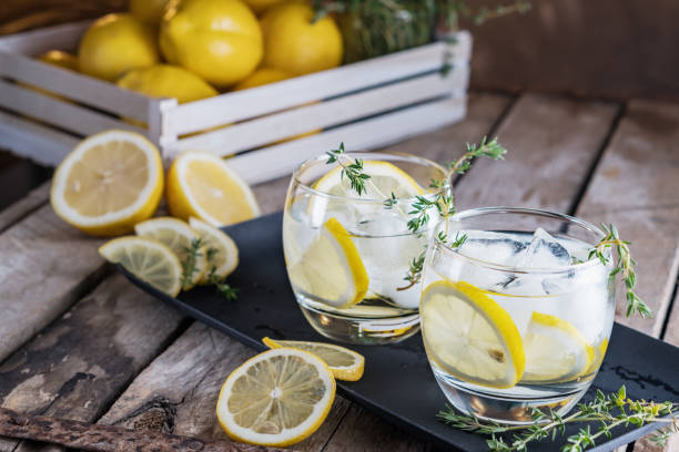 istock Lemon cocktail with thyme and ice on dark rustic background, close-up. Refreshing alcoholic yellow cocktail drink. 940901922