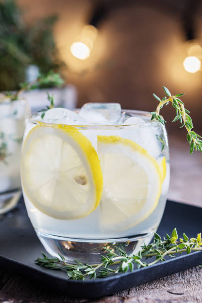 istock Lemon cocktail with thyme and ice on dark rustic background, close-up. Refreshing alcoholic yellow cocktail drink. 940902006