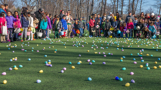 SONY DSCSONY DSCSONY DSCNew Jersey, USA - March 31, 2018: Children hunting for Easter eggs in a sports field in New Jersey while their parents watch
