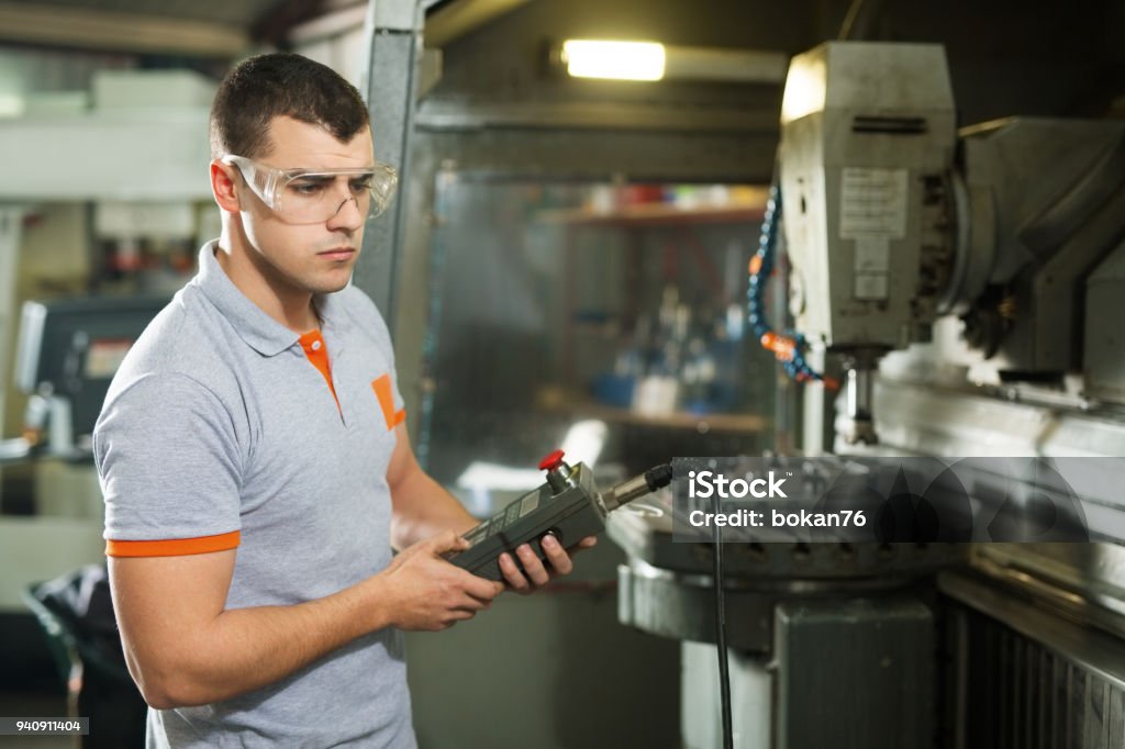 Metal Worker Working On CNC Machine In Factory CNC Machine Stock Photo