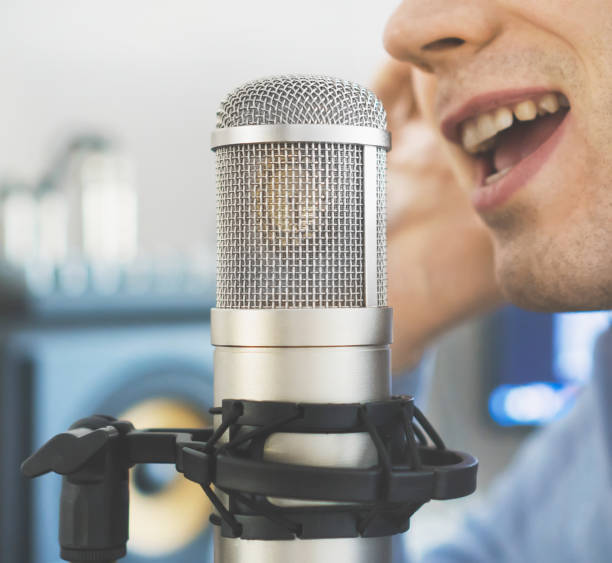 istock Man recording a song in record studio. 940915358