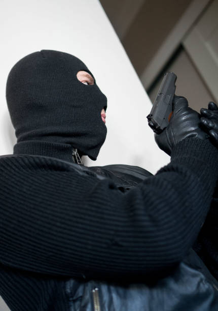 istock Armed man in balaclava hiding behind a wall. 940915412