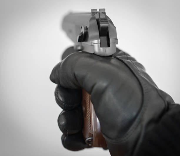 istock Hand in leather glove holding gun and aiming. 940915446