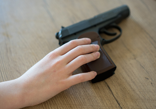 Child taking pistol from the table at home.