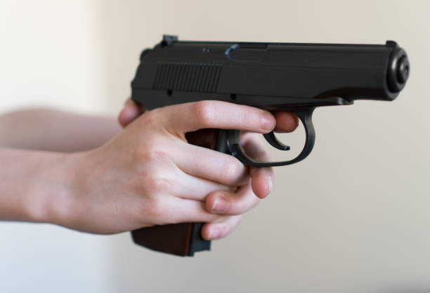 istock Child hand holding a gun and aiming. 940915532