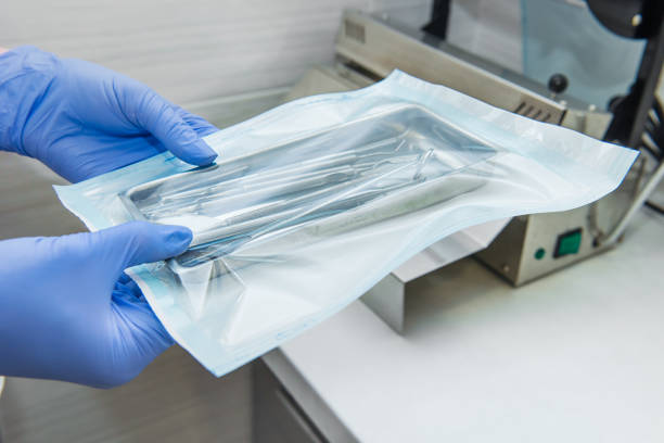 close up dentist assistant's hands holding packaged with vacuum packing machine medical instruments ready for sterilizing in autoclave. dental office. selective focus, space for text. - medical supplies equipment healthcare and medicine surgery imagens e fotografias de stock