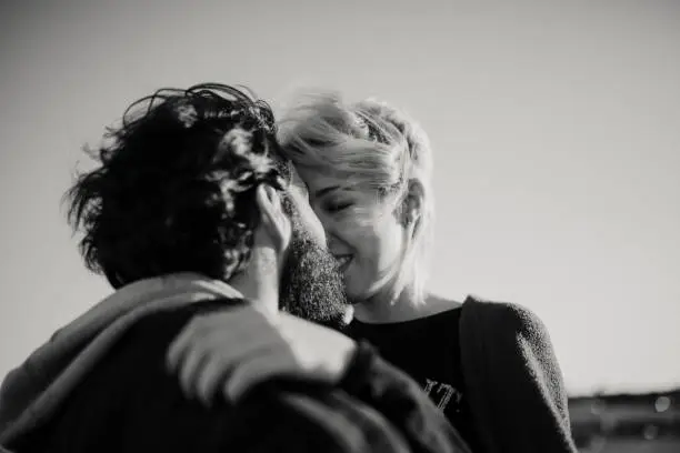 Photo of Close up portrait of couple kissing outdoors in black and white.