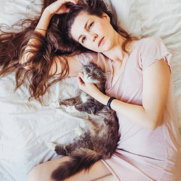 istock Beautiful woman lying in bed with her charming cat 940929336