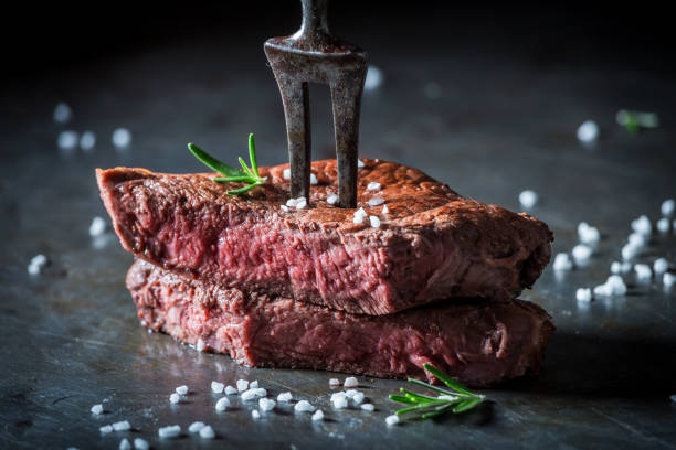 istock Closeup of medium rare steak with salt and herbs 940933622