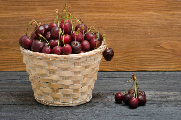 istock Basket with cherries on a wooden table. Copy space 940933970