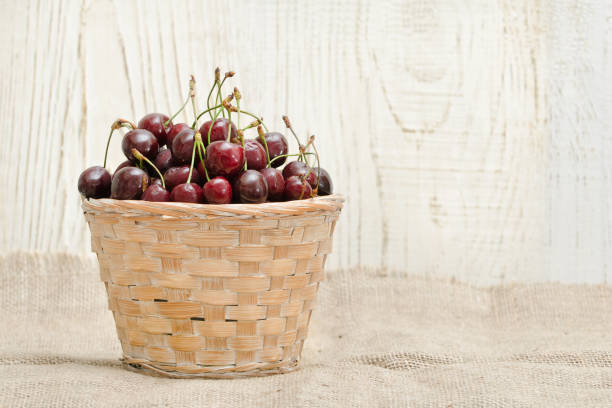 istock Basket with cherries on a wooden table. Copy space 940934010