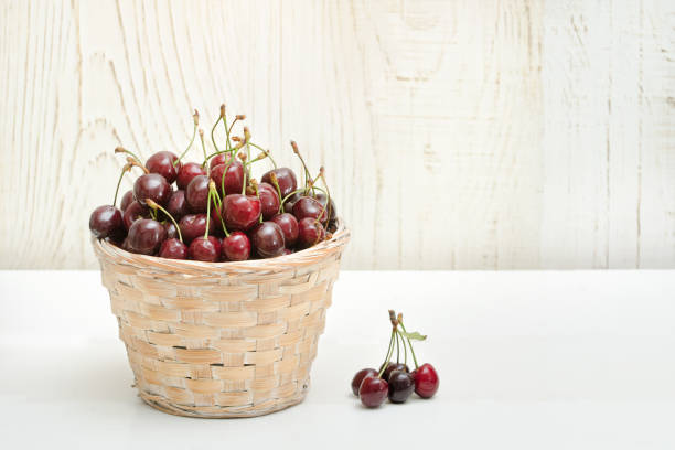 istock Basket with cherries on a white wooden table. Copy space 940934016
