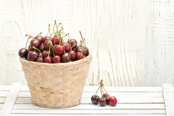 istock Basket with cherries on a white wooden table. Copy space 940934032