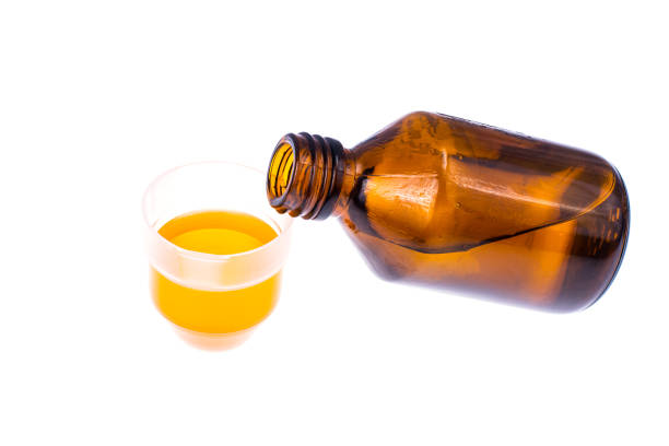 istock Medical bottle and measuring plastic cup with medicinal syrup on white background 940941912
