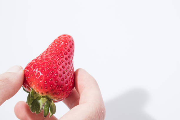 istock A hand gives a strawberry in a white background composition 940945426