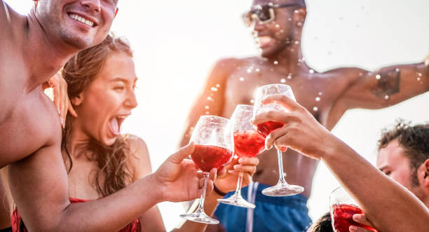 左の男性手のガラス - 旅行、友情、休日、若者のライフ スタイル コンセプトに焦点を当てる専用ボート パーティー - 若い人たちは、夏休みに楽しんで - サングリア ワインを飲む幸せの友人 - friendship party young adult beach ストックフォトと画像