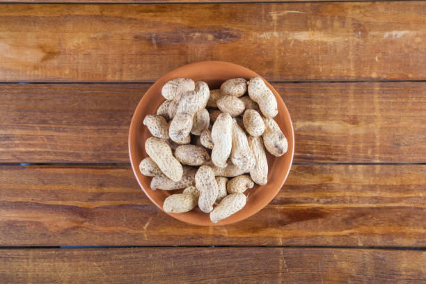 istock Not peeled peanuts on wooden background. Top view 940948688
