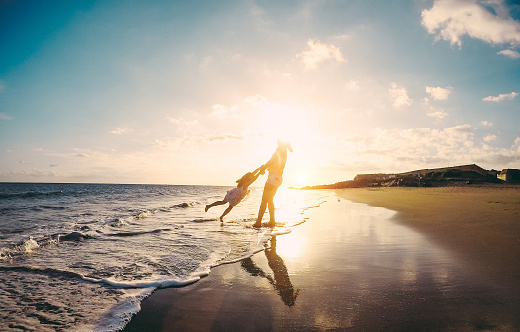 Mother and daughter having fun on tropical beach - Mum playing with her kid in holiday vacation next to the ocean - Family lifestyle and love concept - Focus on silhouettes