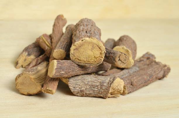 istock Licorice or liquorice root sticks isolated on wood background 940957420